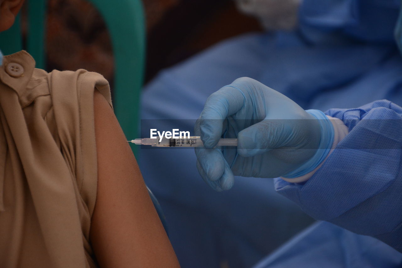 Midsection of doctor injecting vaccine to patient