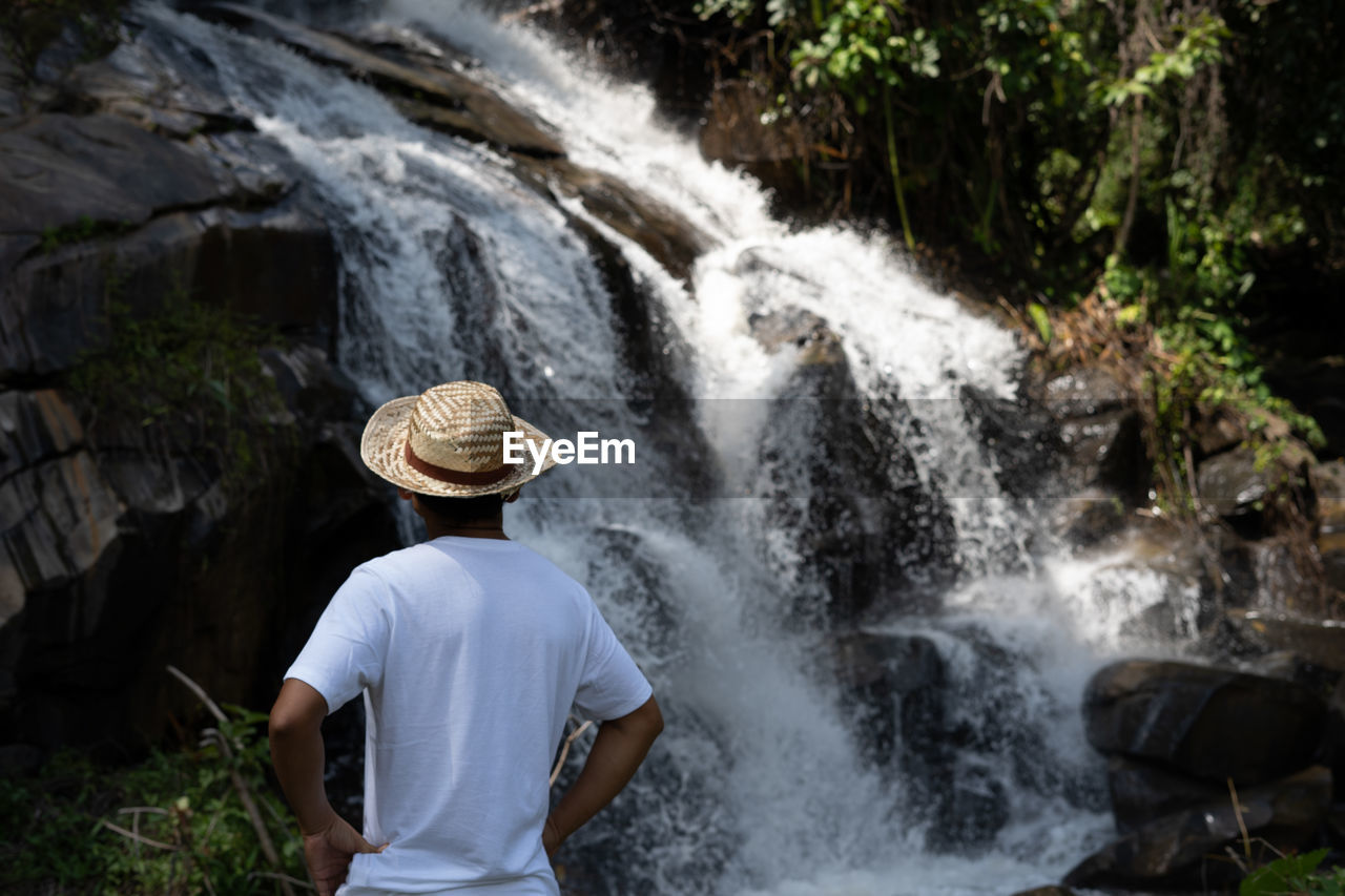 Rear view of man looking at waterfall