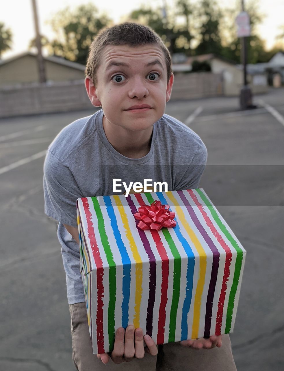 Portrait of a boy holding a large rainbow striped gift box