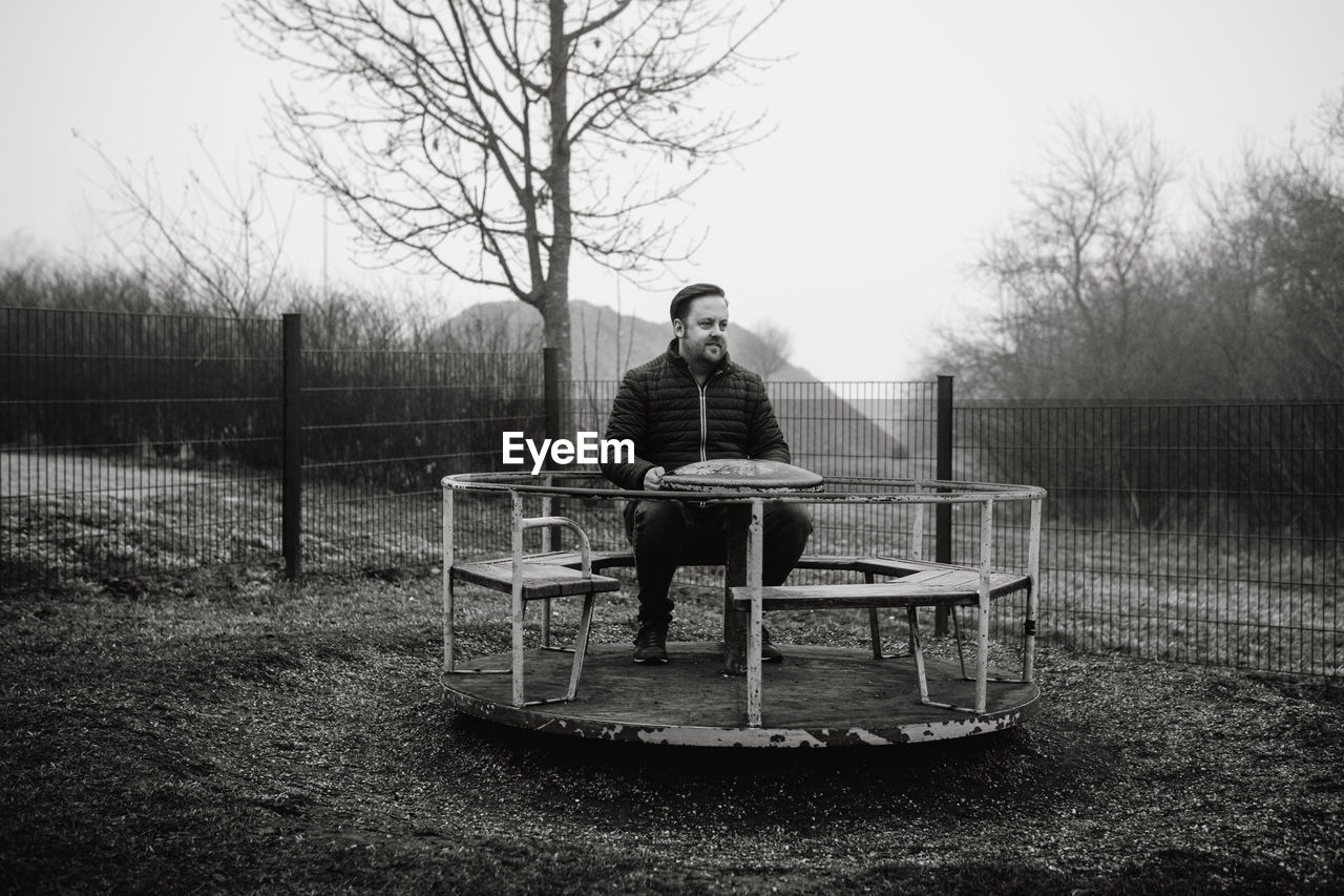 Man sitting on a carousel on a playground 