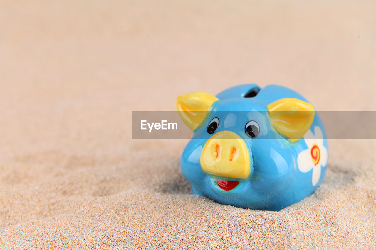 Close-up of piggy bank on sand