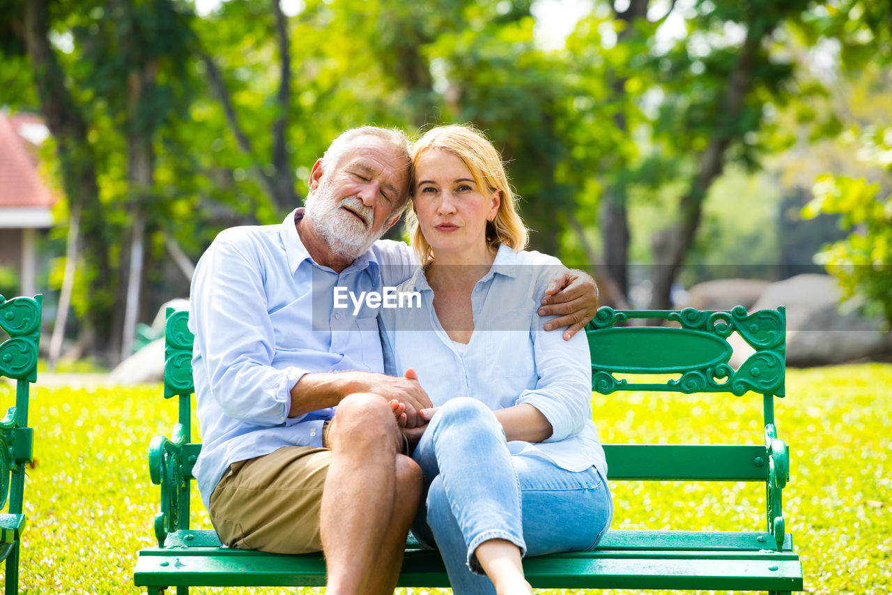 Portrait of couple sitting on bench at park