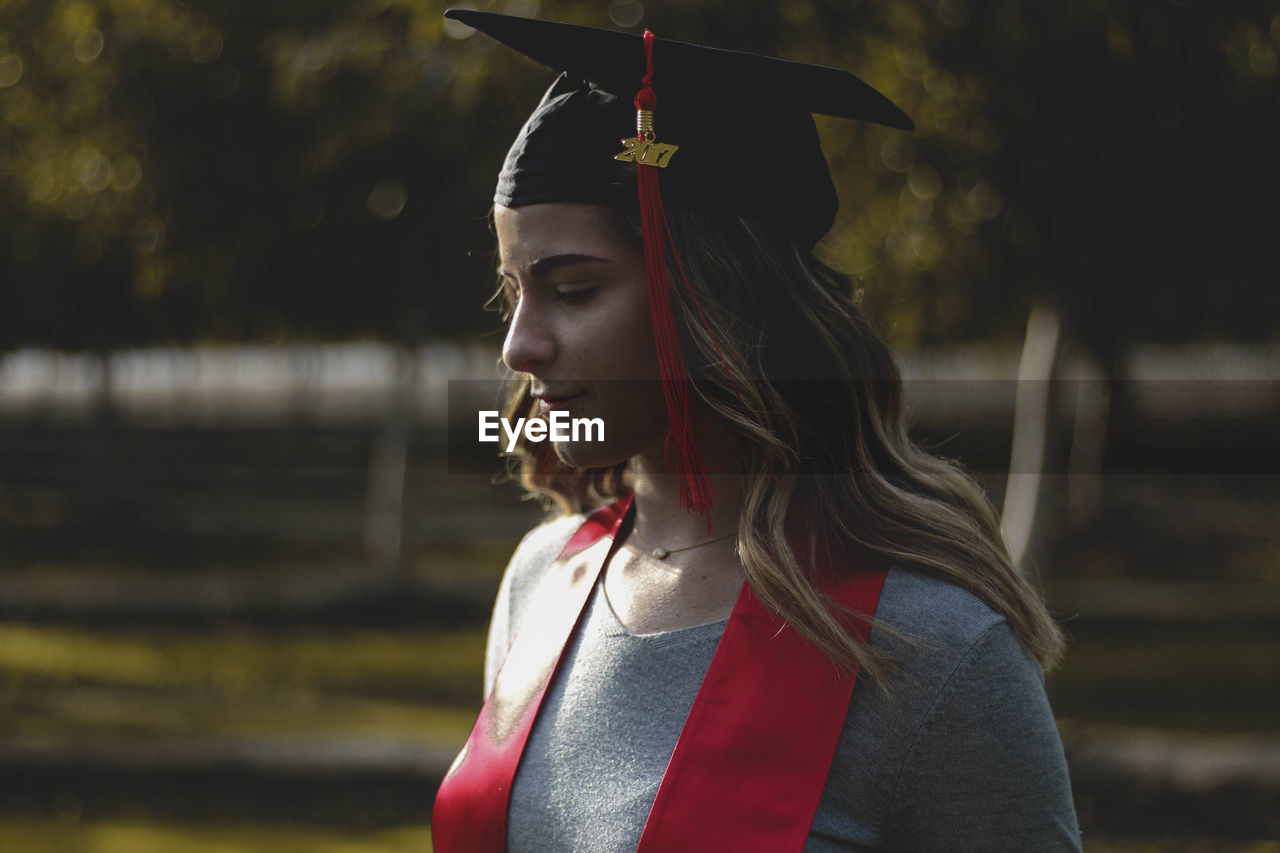 Young woman wearing mortarboard standing at park