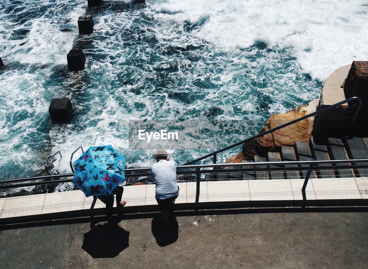 High angle view of friends standing at railing against sea