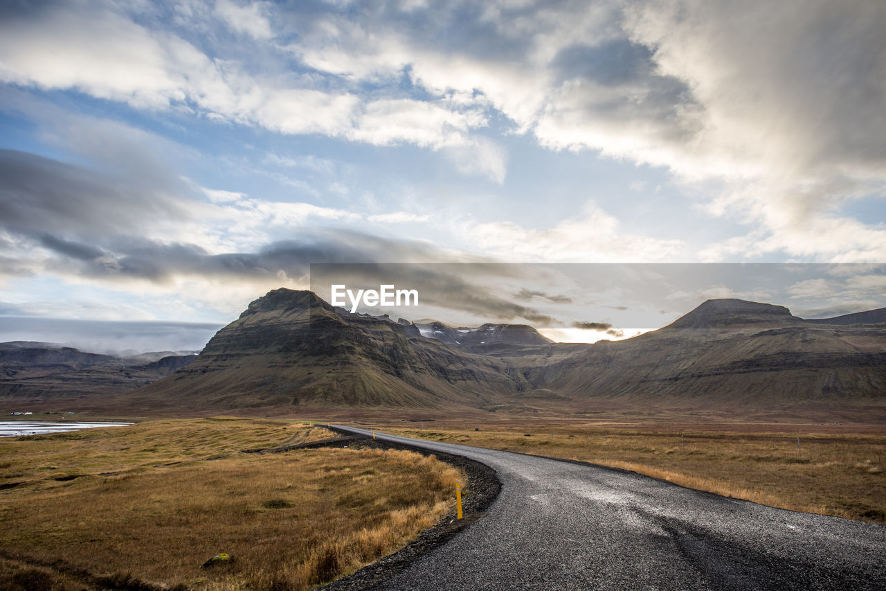 Road leading towards mountains against sky