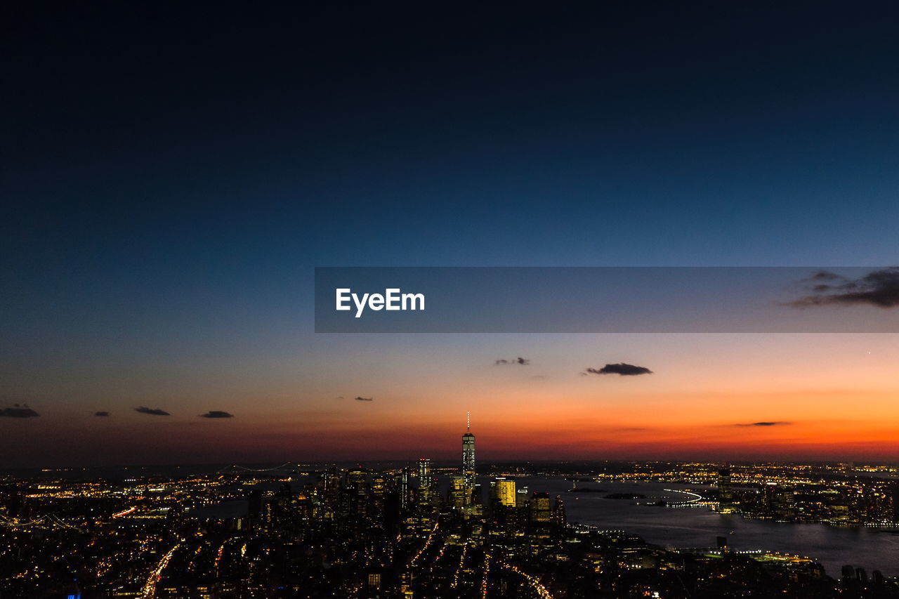 Illuminated cityscape against sky during sunset