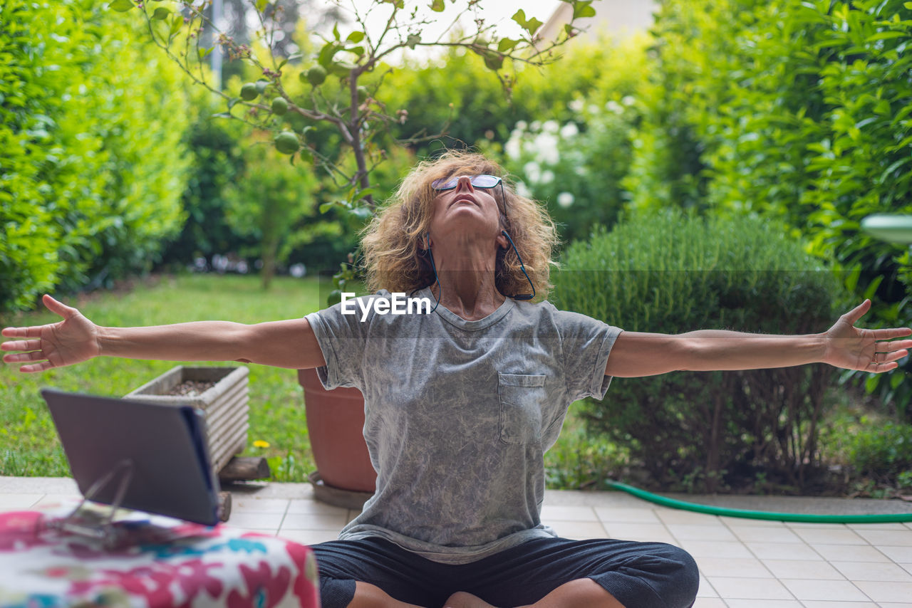 WOMAN USING PHONE WHILE SITTING ON TREE