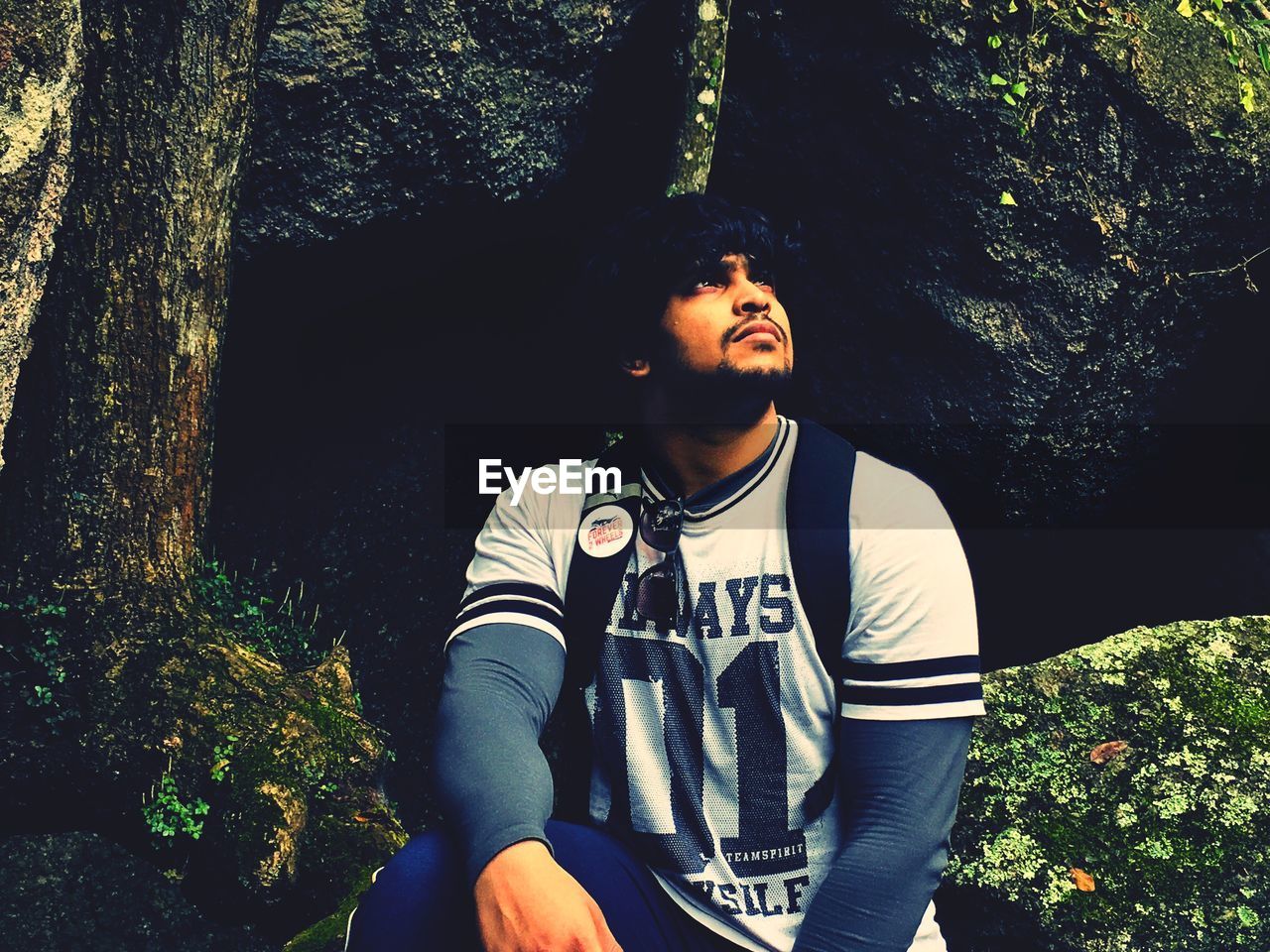 YOUNG MAN SITTING IN FOREST