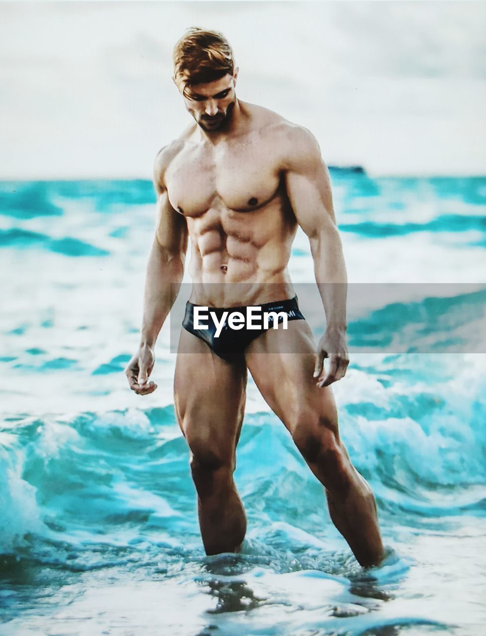 FULL LENGTH OF SHIRTLESS MAN ON BEACH