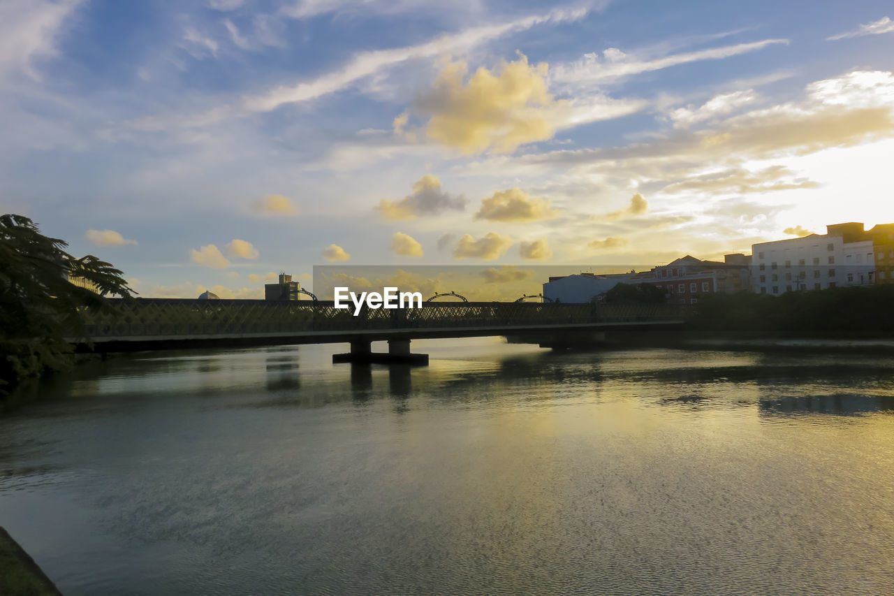 Bridge over river against cloudy sky