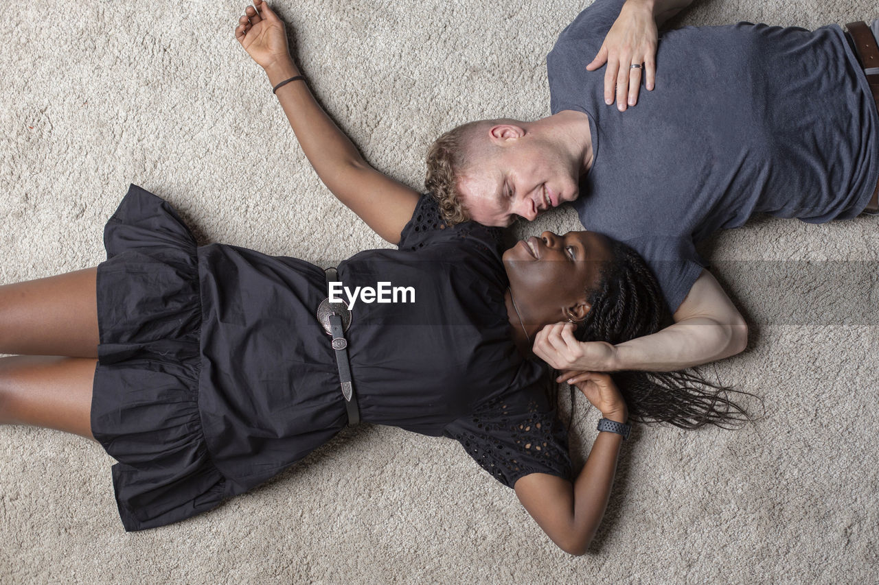 A multiracial couple laying on the floor looking at each other