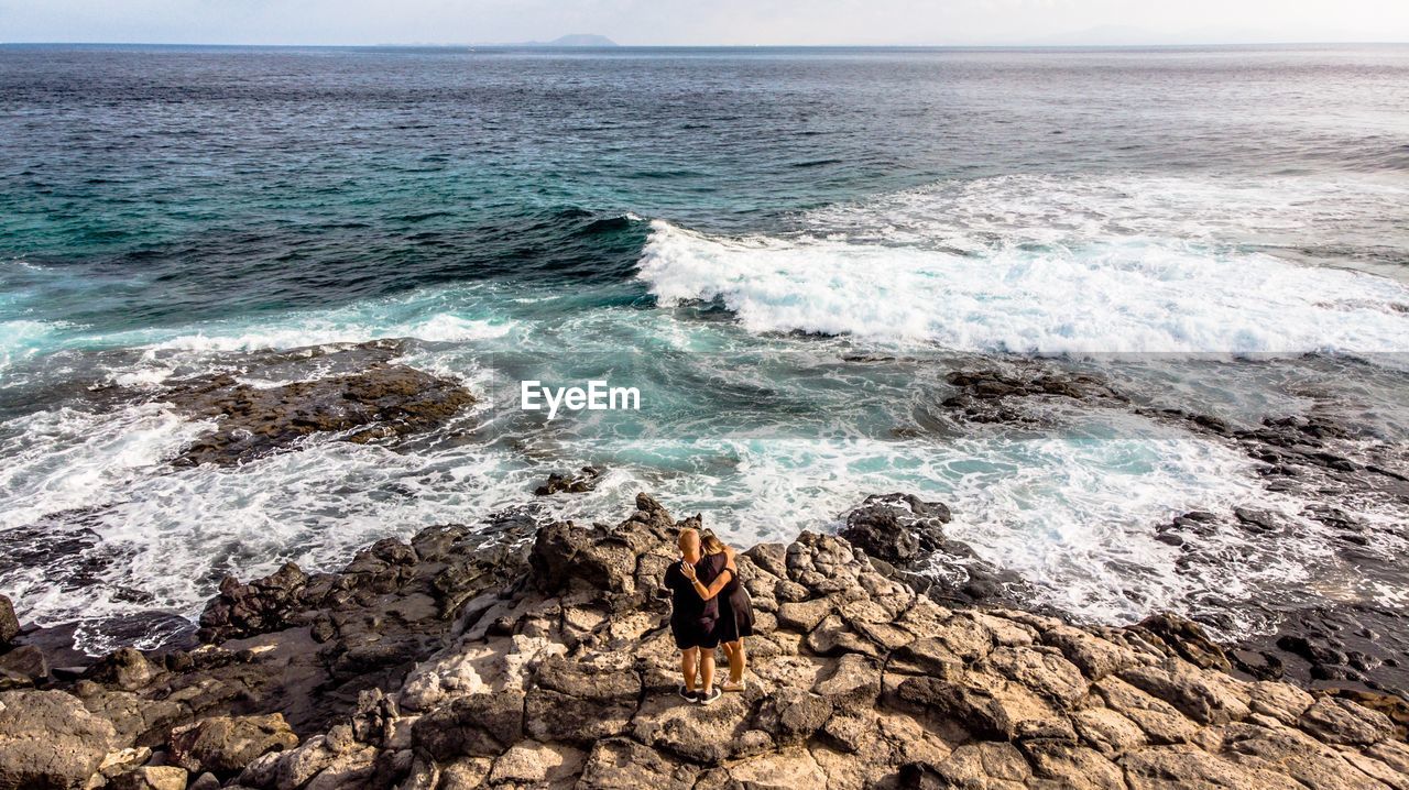 Couple standing on rock at beach