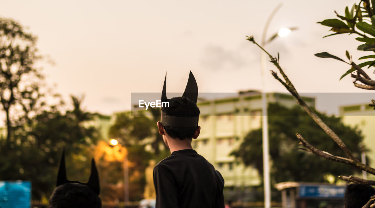 Rear view of boy wearing horn mask against clear sky