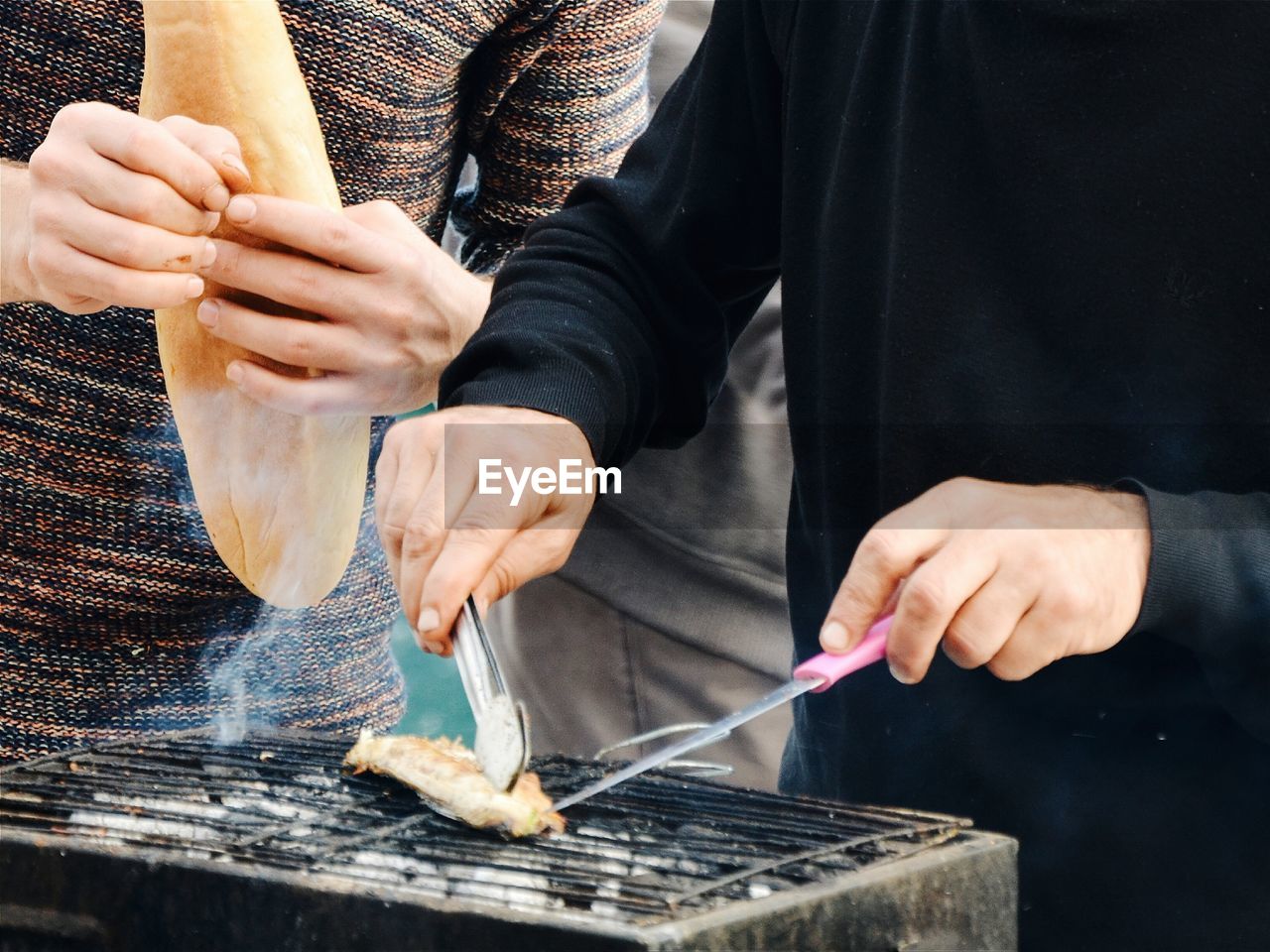 Midsection of men preparing food on barbecue