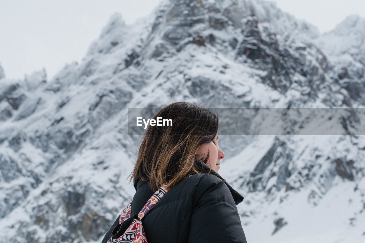 Low angle view of woman standing against snowcapped mountains