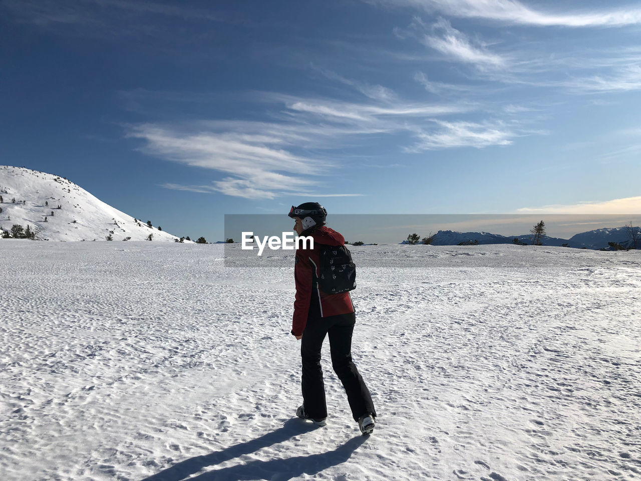 Woman standing on snowcapped mountain against sky