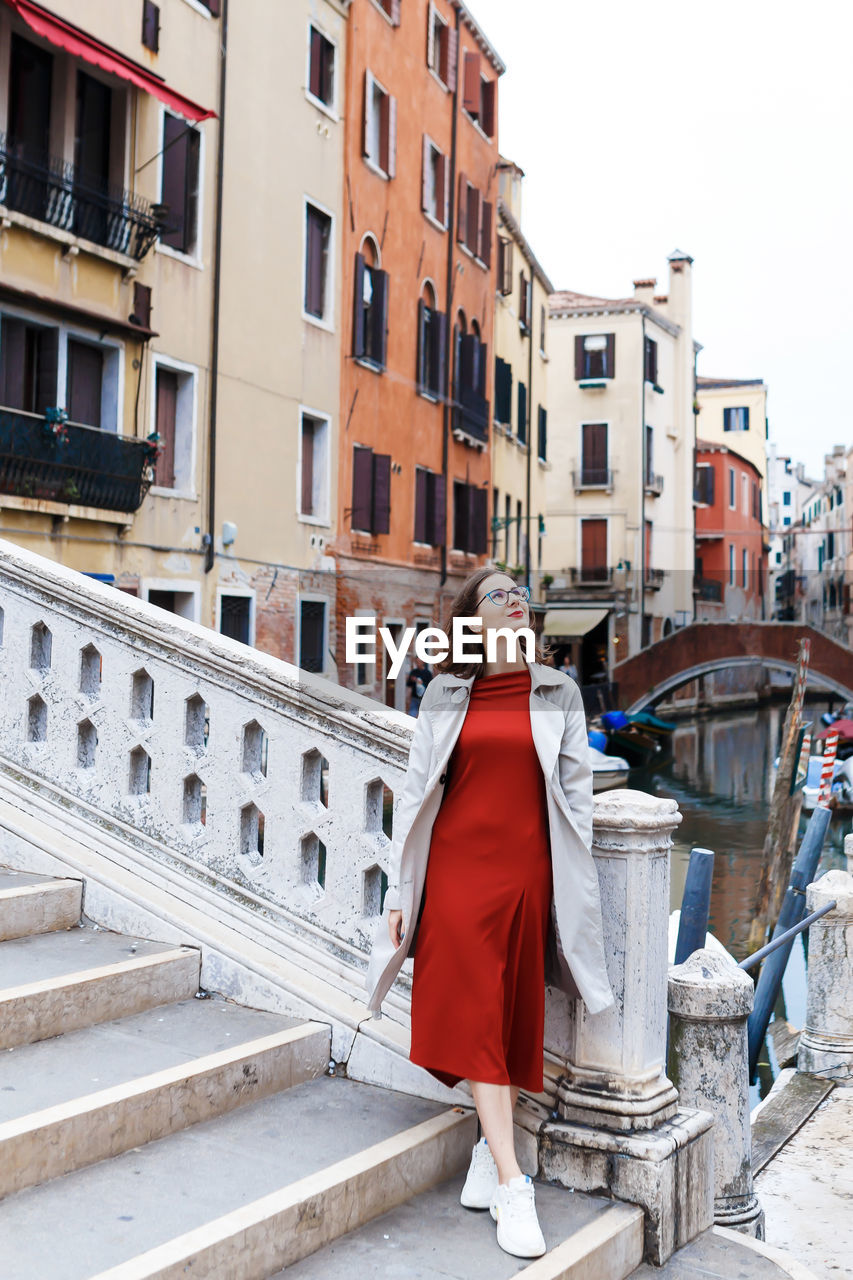 Young tourist in dress and coat on the streets of venice