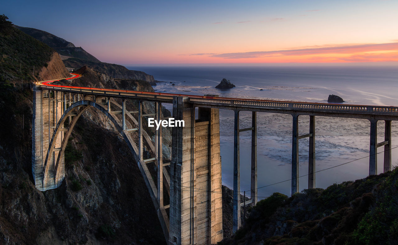 Bridge over sea against sky during sunset