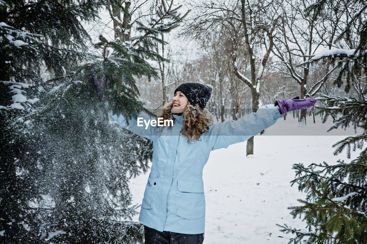 Hello winter, happy wintertime. happy young curly woman with hands raised up celebrating winter