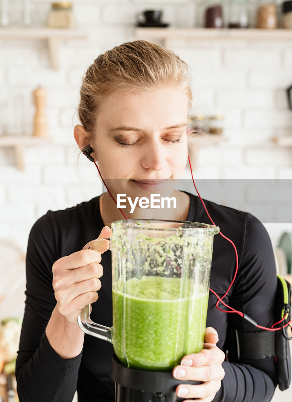 Close-up of woman listening music holding blender
