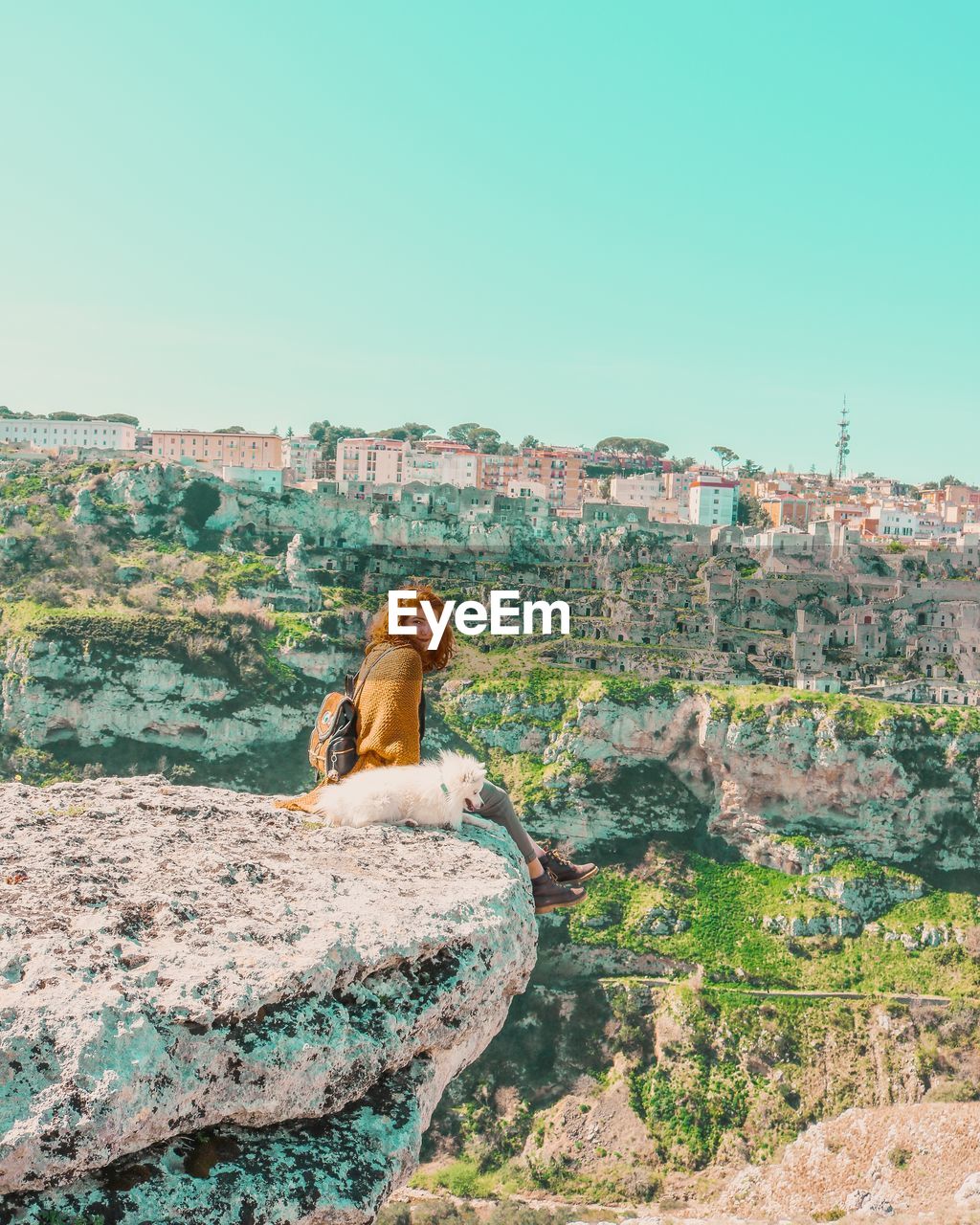 MAN SITTING ON ROCK AGAINST WALL