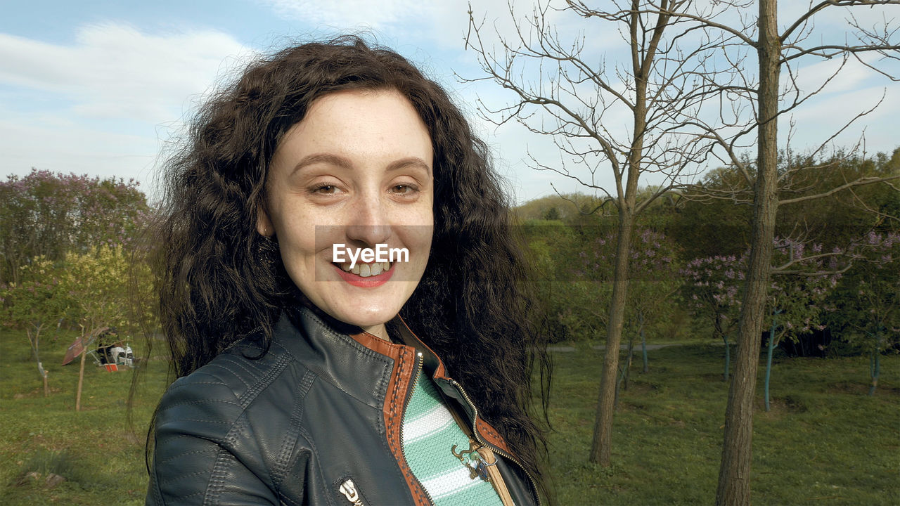 Portrait of smiling young woman standing on field