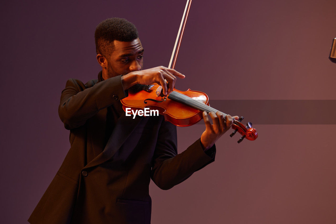 midsection of man playing violin against white background