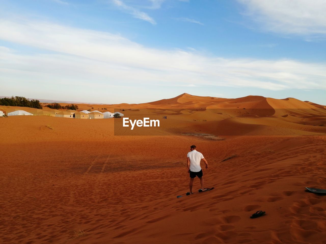 Rear view of man playing on desert against sky
