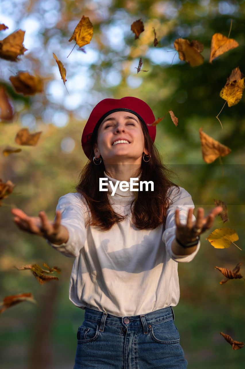 Smiling young woman standing against plants during autumn