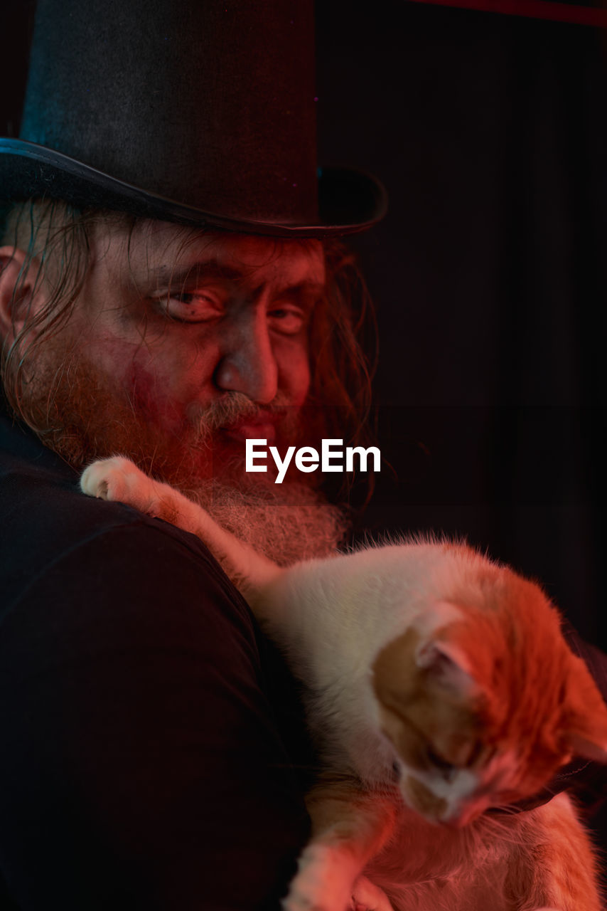 cat, adult, red, hat, nose, men, facial hair, one person, beard, animal, animal themes, portrait, person, human face, clothing, mammal, domestic animals, one animal, pet, fedora, skin, mature adult, indoors, emotion, headshot, carnivore, senior adult, human head, fashion accessory