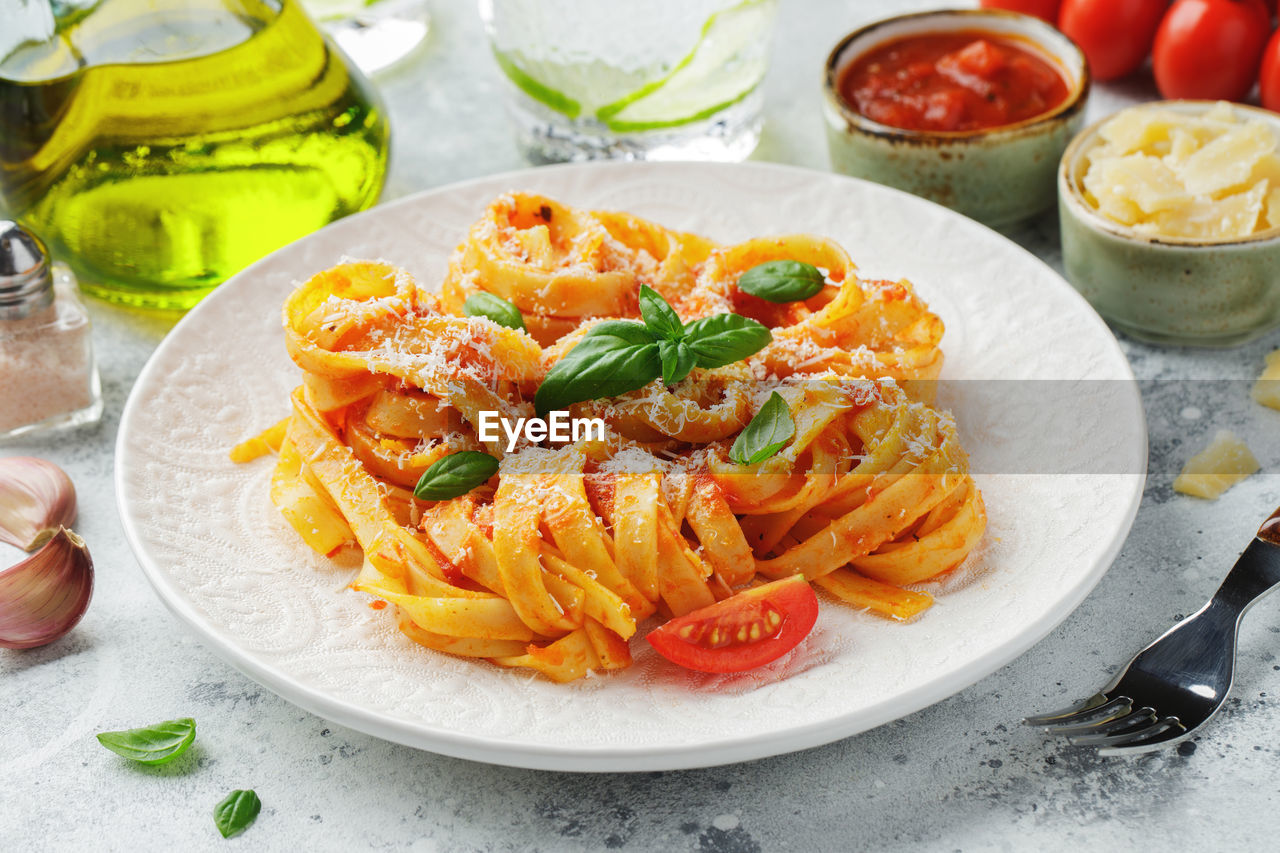 Tasty appetizing classic italian tagliatelle pasta with tomato sauce, cheese parmesan and basil.