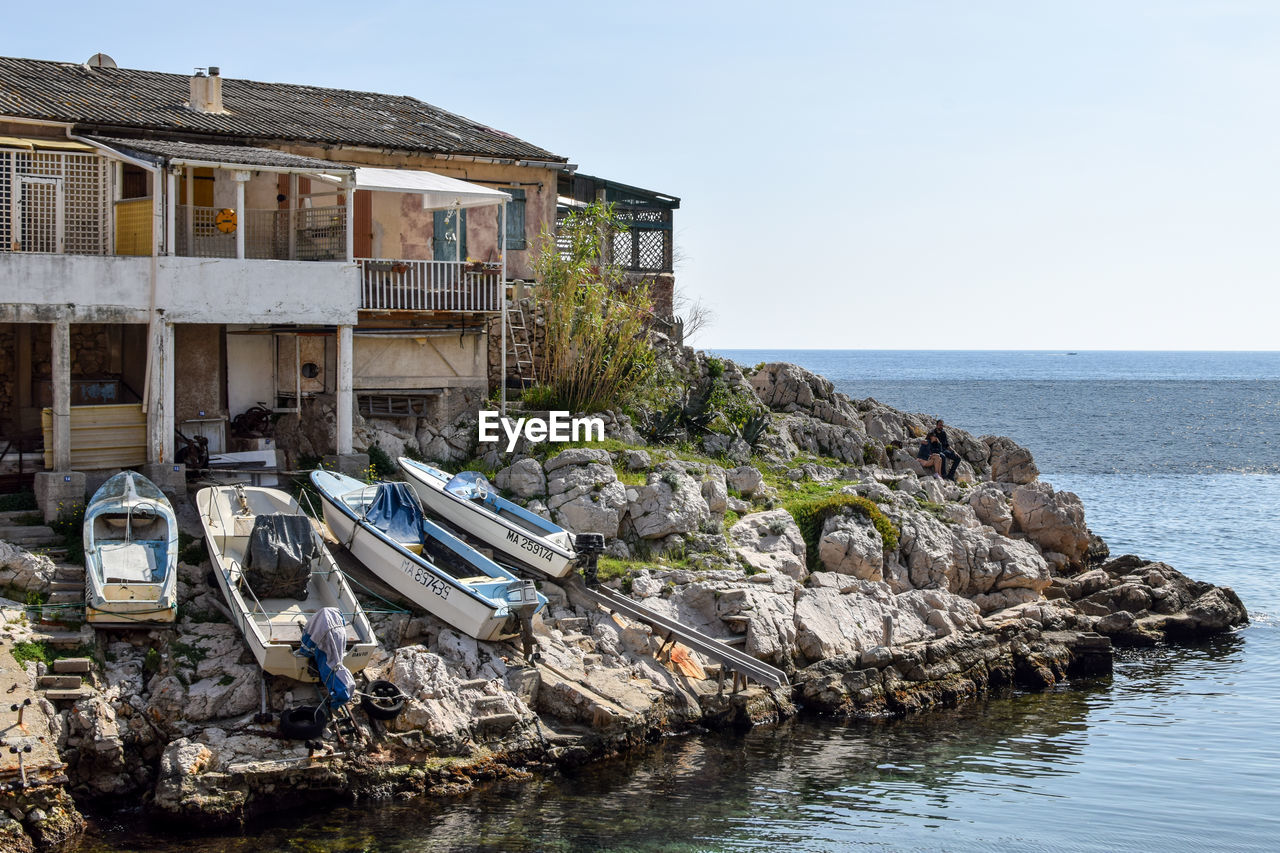 Houses by sea against clear sky