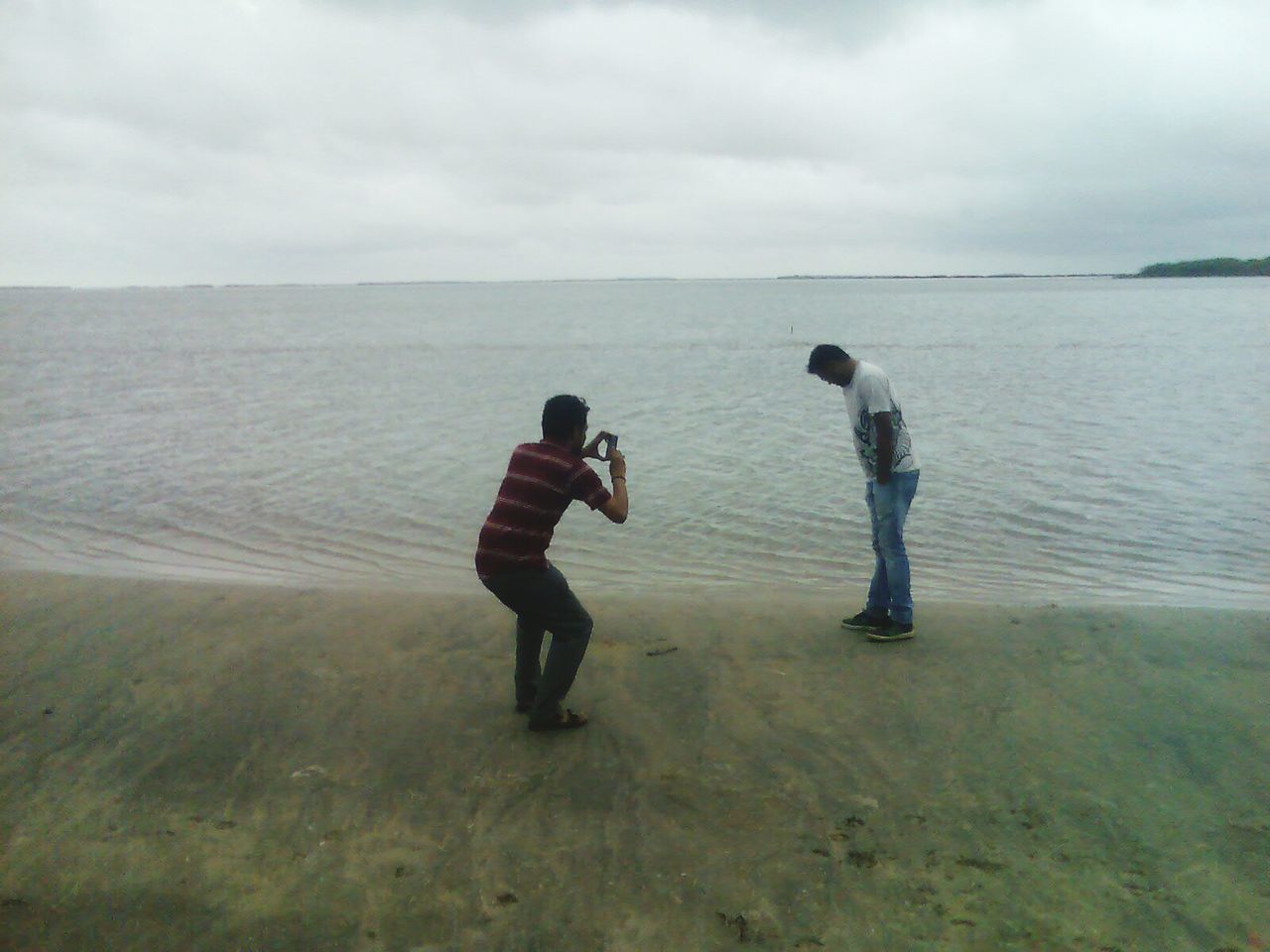 BOYS PLAYING ON BEACH AGAINST SEA