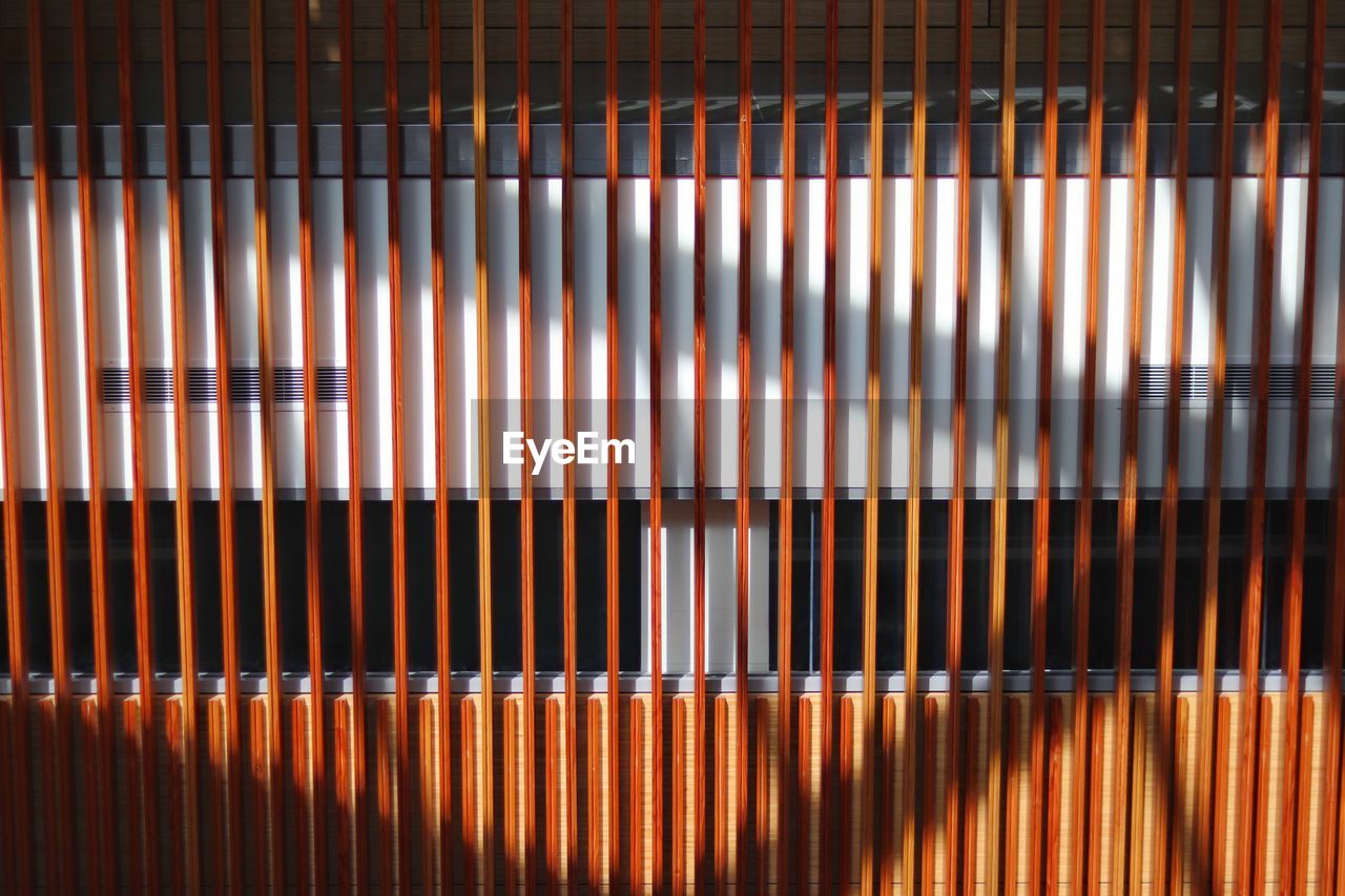 Shadows cast on a line of wooden poles creates a unique perspective on the walkway beyond. 