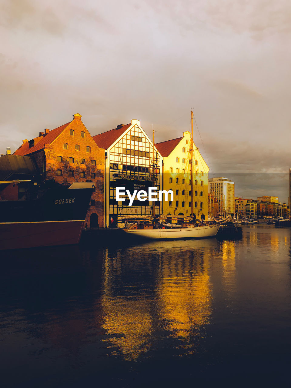 BUILDINGS BY RIVER AGAINST SKY IN CITY