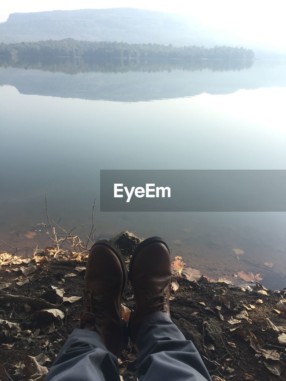 Low section of man on rock against lake