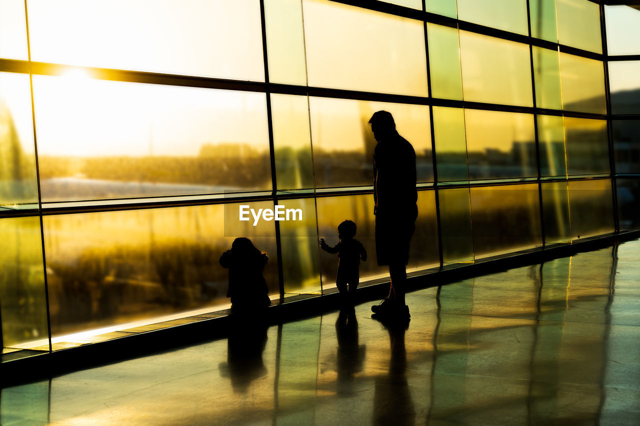 SILHOUETTE PEOPLE STANDING BY GLASS WINDOW