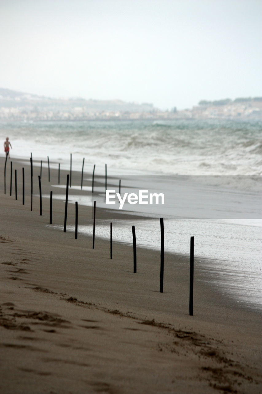 Wooden posts on beach against clear sky