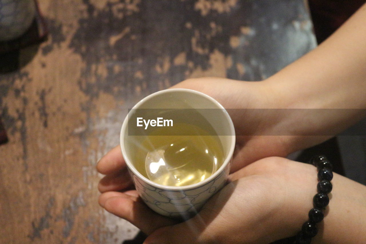 CLOSE-UP OF HAND HOLDING DRINK