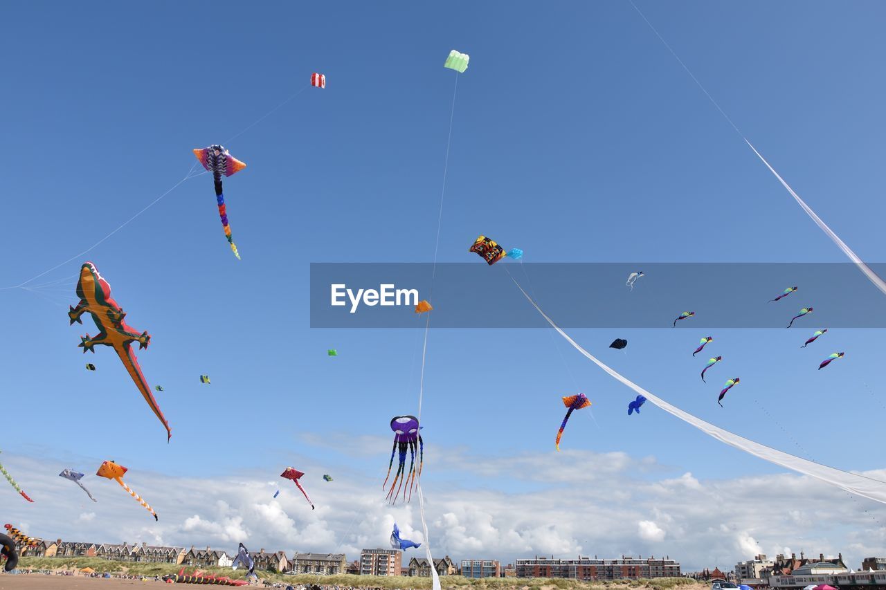 Low angle view of kites flying against blue sky