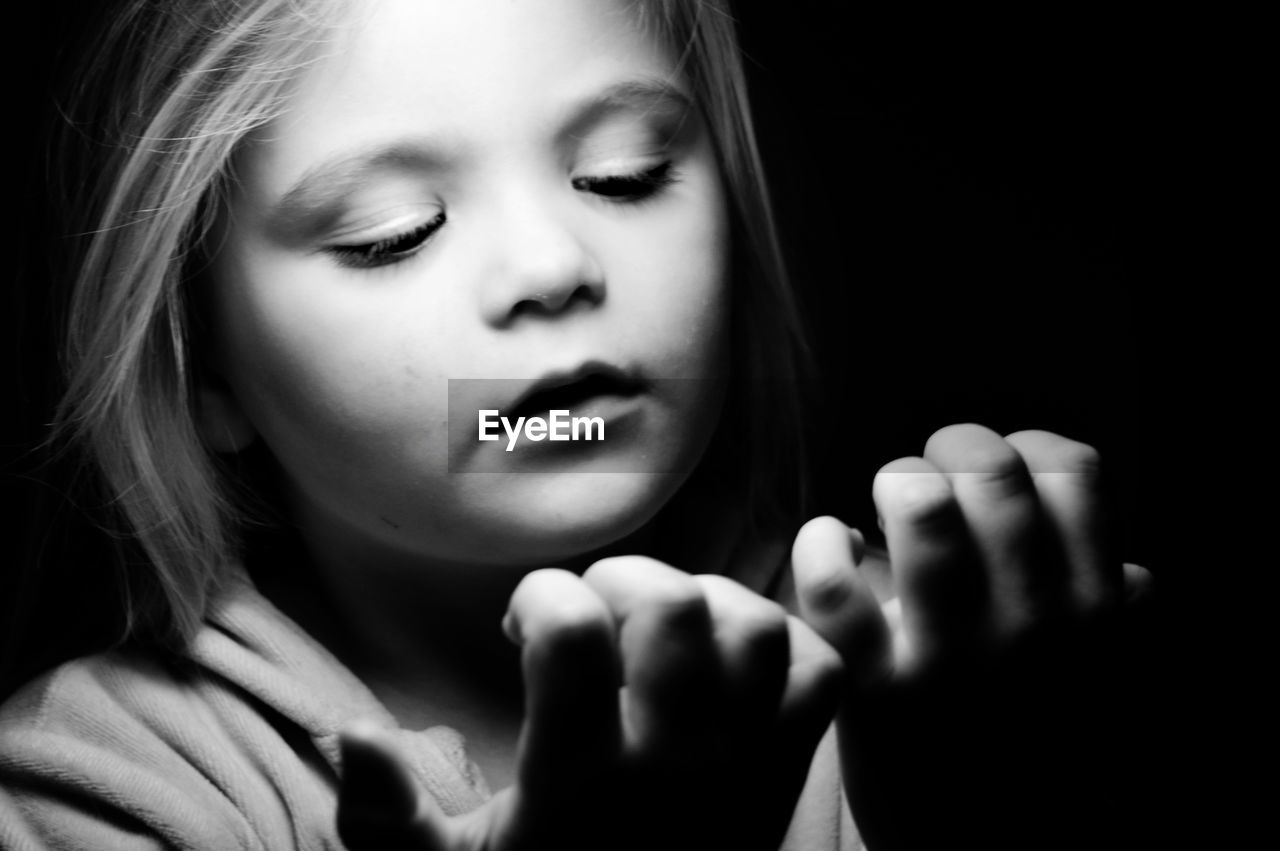 Close-up of cute girl gesturing against black background