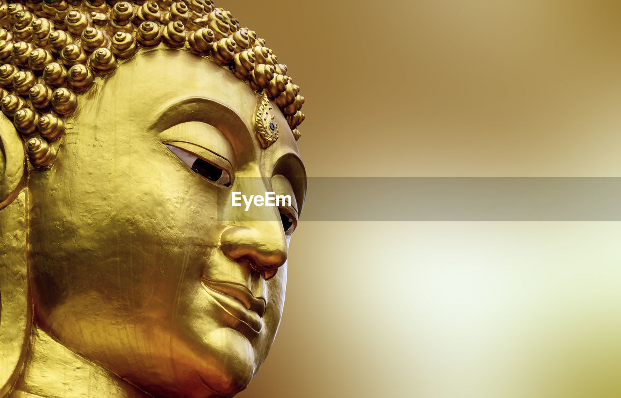 CLOSE-UP OF BUDDHA STATUE AGAINST BACKGROUND