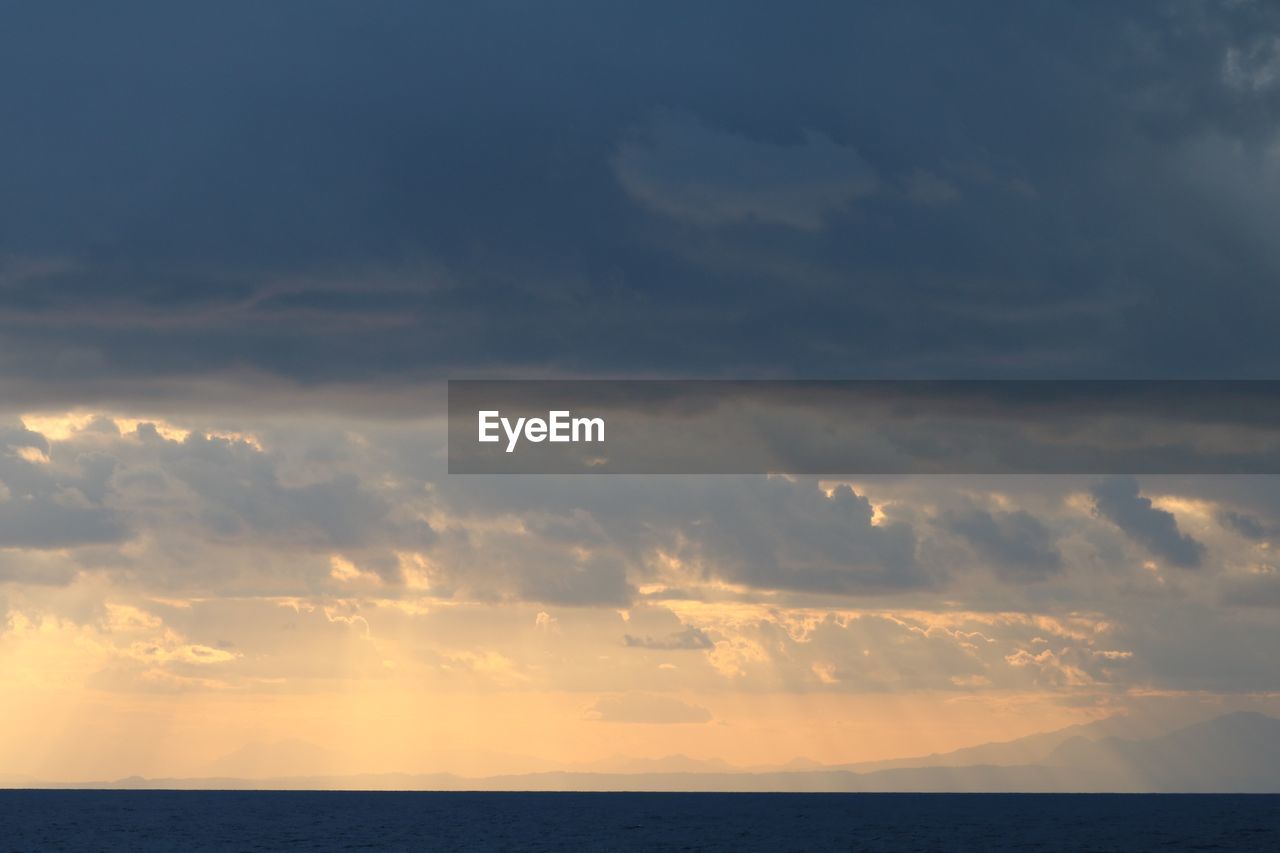 Scenic view of sea against dramatic sky during sunset