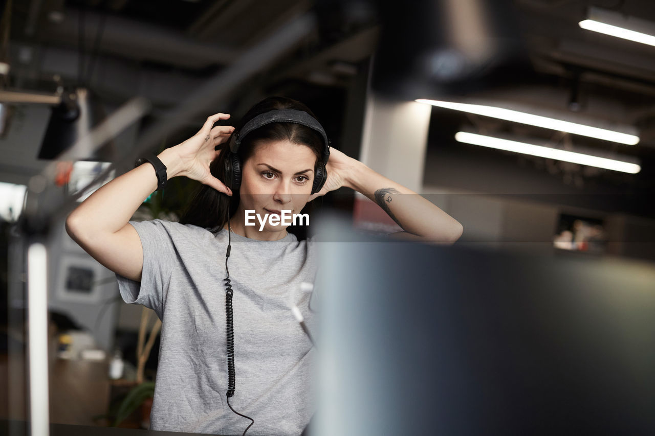 Creative businesswoman wearing headphones while looking at computer monitor in office