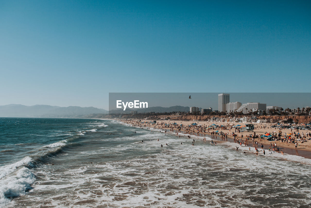 Santa monica beach view with waves crashing and mountains in the background on a clear sunny day