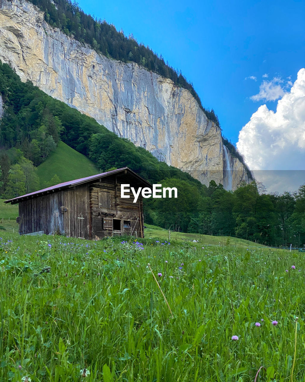 House on field by mountain against sky