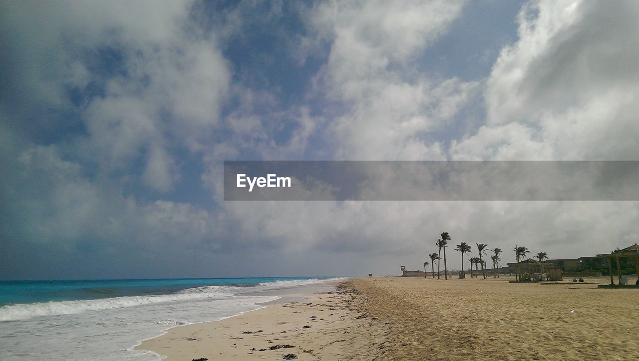 Scenic view of beach against cloudy sky