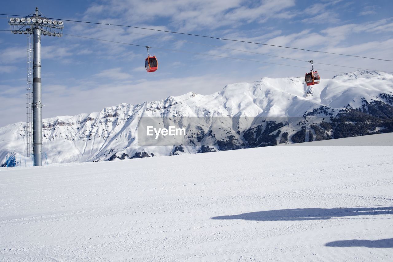 Overhead cable car on snowcapped mountains against sky