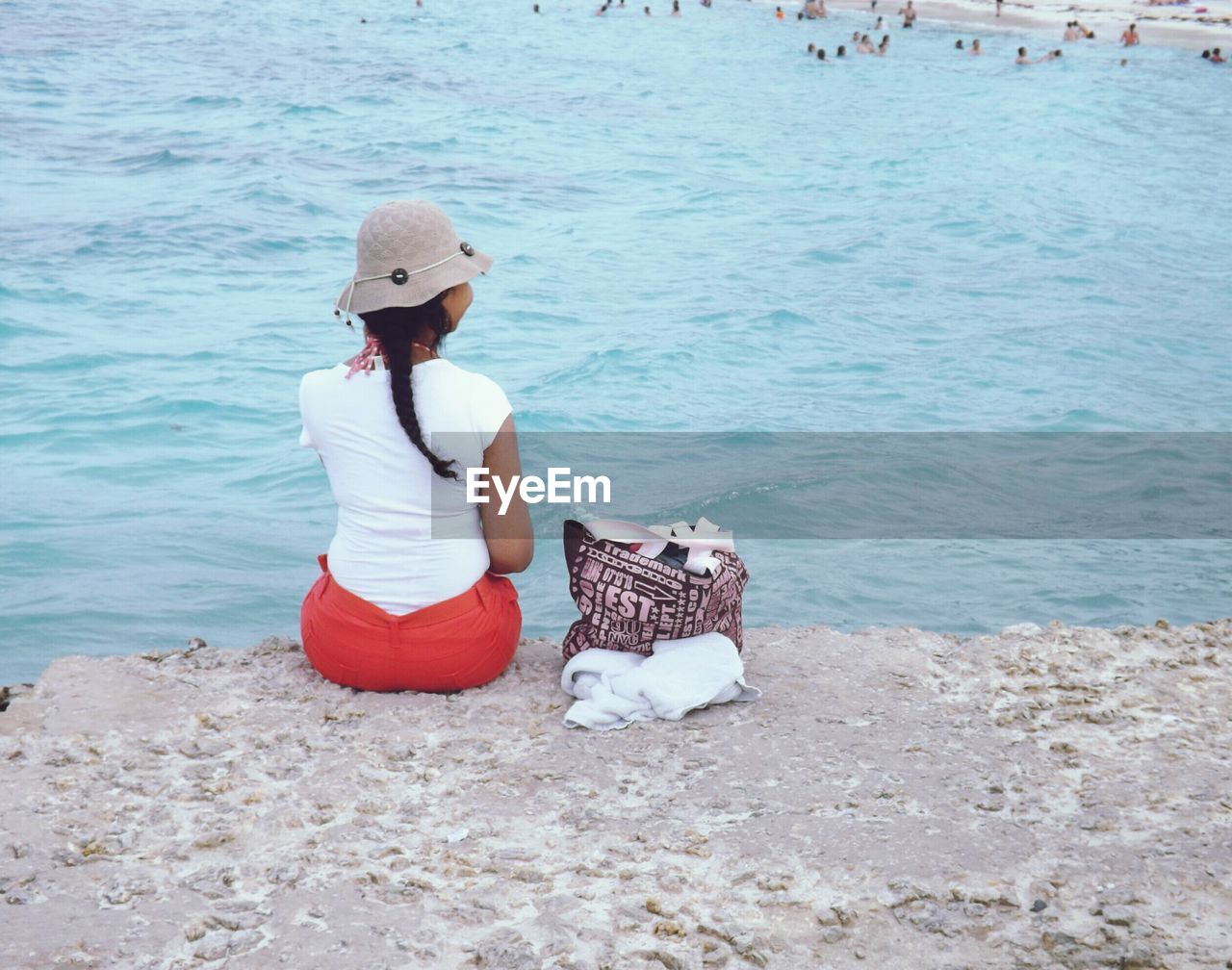 Rear view of woman with purse sitting against sea