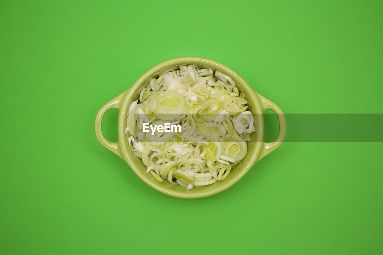 Directly above shot of sliced leek in bowl on green background